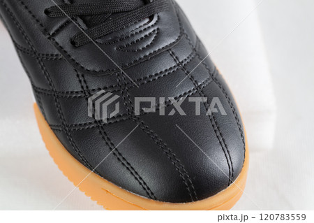 Part of a black leather sneaker with stitching close-up. 120783559