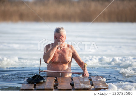 An elderly man bathes in an ice hole on the Orthodox feast of the Epiphany. Take a dip in the icy water. An elderly man bathes in an ice hole on the Orthodox feast of the Epiphany. Take a dip in the icy water. 120783590