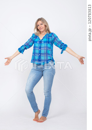 A beautiful middle-aged woman with a slender figure in casual clothes, a shirt and jeans, is photographed in full length. A beautiful middle-aged woman with a slender figure in casual clothes, a shirt and jeans, is photographed in full length. 120783813