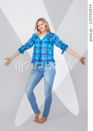 A full-length middle-aged woman in jeans and a shirt. A full-length middle-aged woman in jeans and a shirt. 120783814