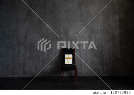 Chair with holiday gift in the interior of a dark living room Chair with holiday gift in the interior of a dark living room 120783989