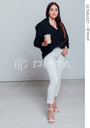 Beautiful fashionable brunette woman with a glass of hot coffee tea on a white background Beautiful fashionable brunette woman with a glass of hot coffee tea on a white background 120784235