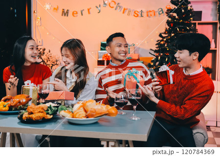 Friends opening Christmas gifts in living room 120784369