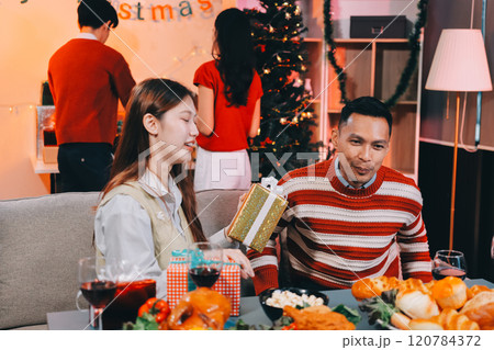 Friends opening Christmas gifts in living room 120784372