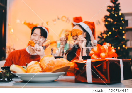 Group of young Asian man and women as friends having fun at a New Year's celebration, holding gift boxes standing by Christmas tree decoration, midnight countdown Party at home with holiday season. 120784416
