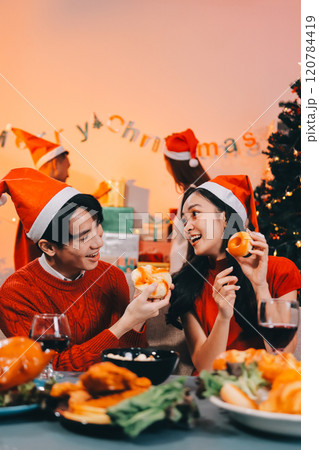 Group of young Asian man and women as friends having fun at a New Year's celebration, holding gift boxes standing by Christmas tree decoration, midnight countdown Party at home with holiday season. 120784419