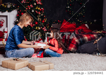 Mother with daughter at Christmas tree with gifts garlands decorated for the new year 120784441
