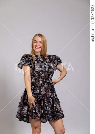 Beautiful blonde woman in summer dark dress on gray background 120784627