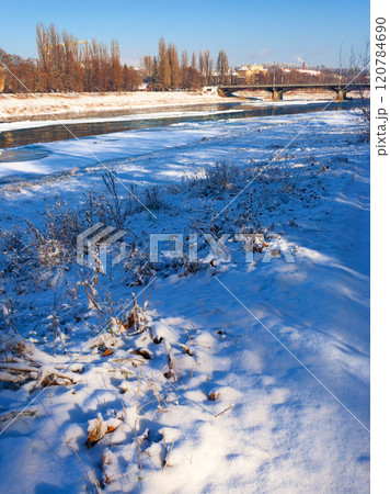 uzhhorod, ukraine - 03 jan, 2009: transportation bridge over the frozen river uz in winter. sunny weather. urban landscape of the old city downtown. white season in town uzhhorod, ukraine - 03 jan, 2009: transportation bridge over the frozen river uz in winter. sunny weather. urban landscape of the old city downtown. white season in town 120784690