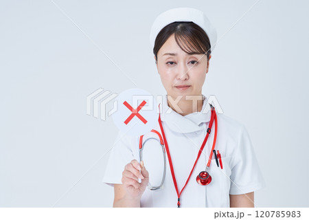 バツが書かれたプレートを持つ白衣姿の女性 120785983