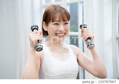 ダンベルでトレーニングする若い女性 120787067
