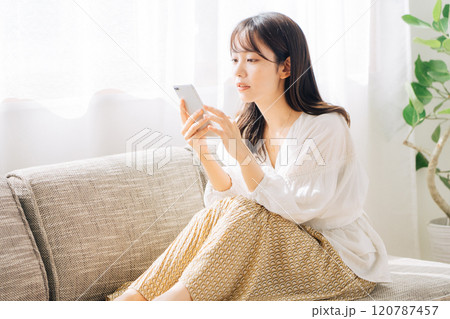 ソファに座ってスマホを見る女性 120787457