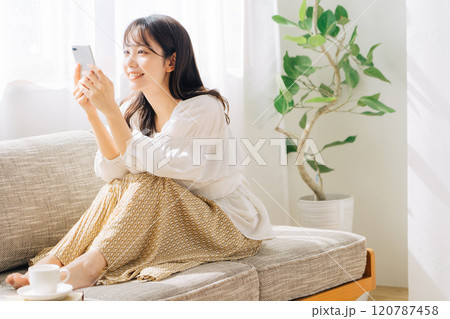 ソファに座ってスマホを見る女性 120787458