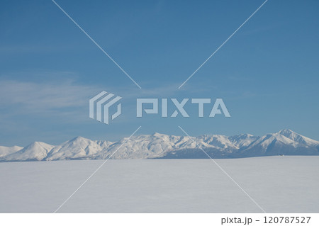 冬の晴れた日の雪原と山並み 120787527
