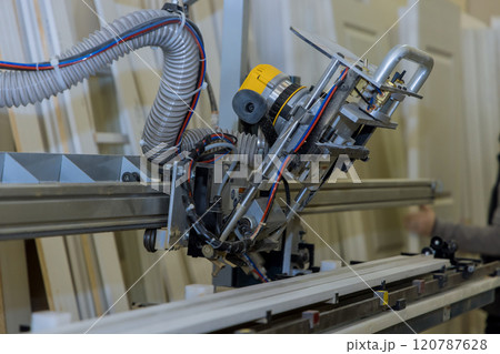 Woodworking machine in factory, showing an automated cutting drilling tool used for door with hose attached, for dust extraction machine is positioned Woodworking machine in factory, showing an automated cutting drilling tool used for door with hose attached, for dust extraction machine is positioned 120787628