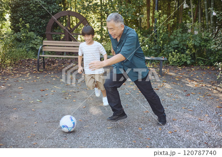 サッカーをするおじいちゃんと孫 120787740