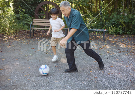サッカーをするおじいちゃんと孫 120787742