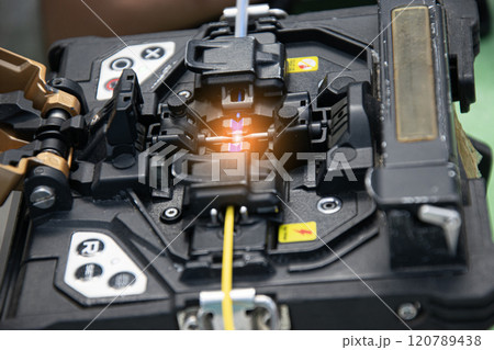 The technician is connecting the fiber optic cable with a tool. 120789438