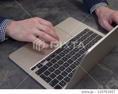 Businessman working on a gold laptop in a modern office, browsing online with focus and efficiency. 120791087