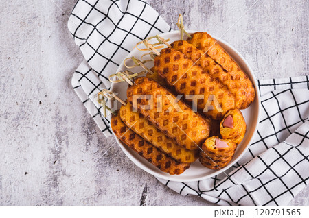 Close up of stack of homemade corn dogs with sausage on a plate on a table top view Close up of stack of homemade corn dogs with sausage on a plate on a table top view 120791565
