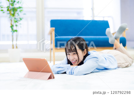 タブレットでYouTube動画を寝転んで見る若い女性　休日　リラックス　動画視聴 120792298
