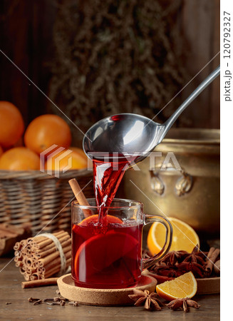 Mulled wine is poured into a glass cup. Mulled wine is poured into a glass cup. 120792327