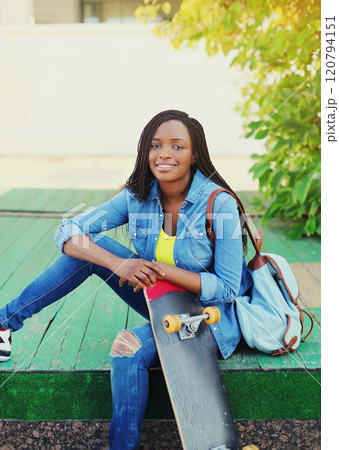 Portrait of happy smiling young african woman model posing with skateboard in the city Portrait of happy smiling young african woman model posing with skateboard in the city 120794151