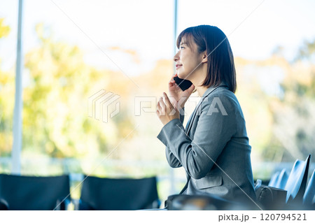 スマホで会話をする女性会社員　空港のロビーで誰かを待つ女性　OL　働くオフィスレディ 120794521