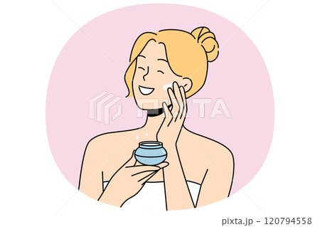 Woman applies anti-aging cream to face to stay beautiful, standing in bath towel after shower. 120794558