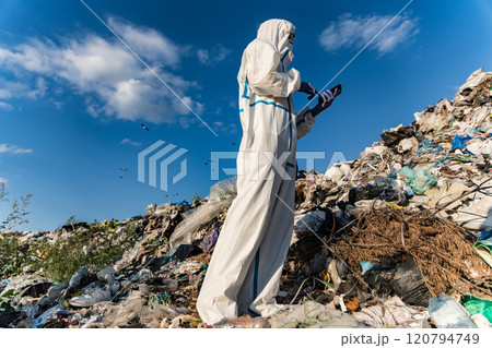 Man in bacteriological protective in a landfill. Landfill with household waste. Environment pollution Man in bacteriological protective in a landfill. Landfill with household waste. Environment pollution 120794749