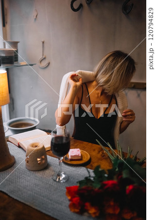 Cozy evening in a cafe with a woman enjoying wine and dessert by warm candlelight 120794829