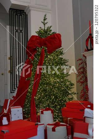 large Christmas tree with red bow and toys. New Year's decor, gift box on Christmas Eve. large Christmas tree with red bow and toys. New Year's decor, gift box on Christmas Eve. 120795322