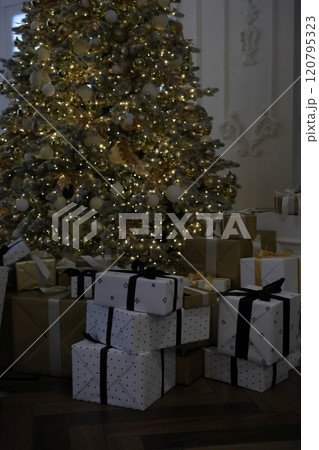 large Christmas tree with garland and toys. New Year's decor, gift box on Christmas Eve large Christmas tree with garland and toys. New Year's decor, gift box on Christmas Eve 120795323
