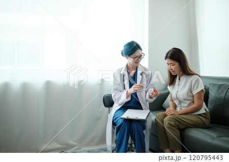 A woman is sitting on a couch while a doctor shows her a toothbrush A woman is sitting on a couch while a doctor shows her a toothbrush 120795443