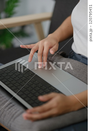A woman is sitting on a couch with a laptop on her lap A woman is sitting on a couch with a laptop on her lap 120795451