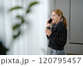 A woman is talking on her cell phone while holding a cup of coffee 120795457
