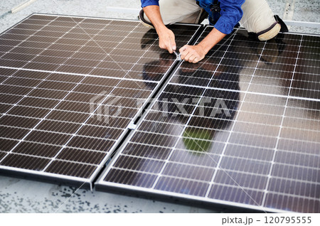 Worker building photovoltaic solar panel system on rooftop of house. Close up of man engineer installing solar module with help of wrench outdoors. Alternative and renewable energy generation concept. Worker building photovoltaic solar panel system on rooftop of house. Close up of man engineer installing solar module with help of wrench outdoors. Alternative and renewable energy generation concept. 120795555