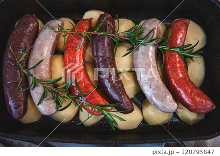 Close-up of bowl with raw homemade blood sausage, pork sausage and chorizo in oven with potatoes. homemade traditional food Close-up of bowl with raw homemade blood sausage, pork sausage and chorizo in oven with potatoes. homemade traditional food 120795847