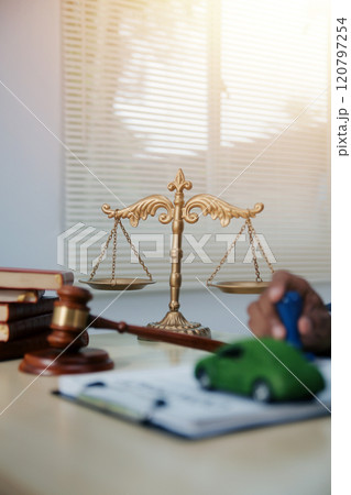 Judge gavel and miniature car symbolize auction or court case against driver who has accident and receiving vehicle insurance payment be on table in front of hands of lawyers. Selective focus Judge gavel and miniature car symbolize auction or court case against driver who has accident and receiving vehicle insurance payment be on table in front of hands of lawyers. Selective focus 120797254