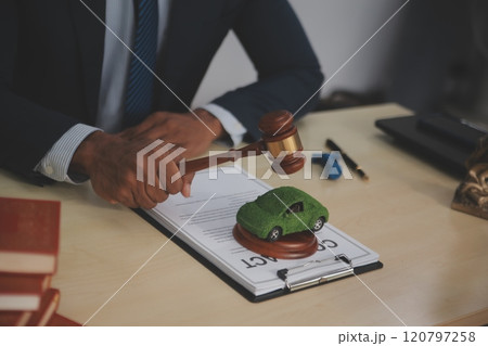 Judge gavel and miniature car symbolize auction or court case against driver who has accident and receiving vehicle insurance payment be on table in front of hands of lawyers. Selective focus Judge gavel and miniature car symbolize auction or court case against driver who has accident and receiving vehicle insurance payment be on table in front of hands of lawyers. Selective focus 120797258