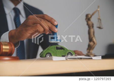 Judge gavel and miniature car symbolize auction or court case against driver who has accident and receiving vehicle insurance payment be on table in front of hands of lawyers. Selective focus Judge gavel and miniature car symbolize auction or court case against driver who has accident and receiving vehicle insurance payment be on table in front of hands of lawyers. Selective focus 120797265