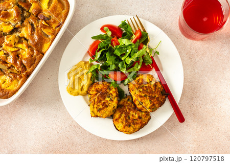 Enjoy a delicious and healthy breakfast with zucchini pancakes, fresh lettuce, and tomatoes, complemented by cherry compote and a slice of peach pie for a flavorful start to your day 120797518