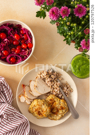 A healthy meal of green buckwheat with chicken breast, zucchini pancakes, fermented vegetable salads and celery cucumber smoothie 120797526