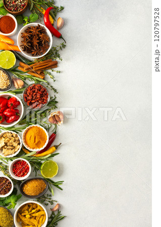 Various cooking spices and herbs spread across a neutral gray background, showcasing their rich, natural tones, top view and copy space 120797528