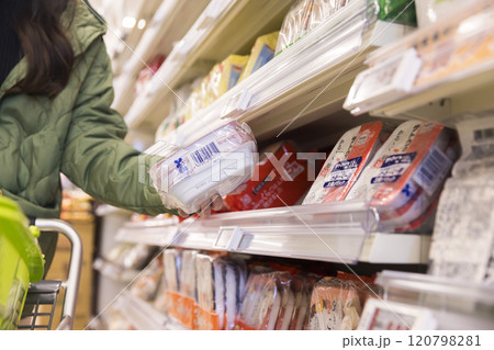 スーパーでパックご飯を買う女性手元 120798281