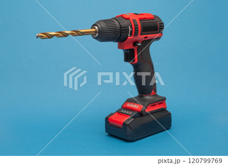 a cordless screwdriver with a drill bit. on the blue 120799769