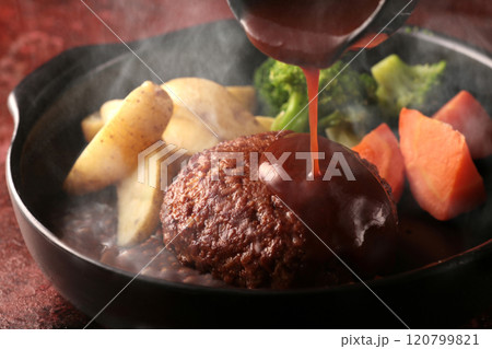 鉄板の上で焼く熱々の湯気の上がるジューシーなハンバーグステーキ 120799821