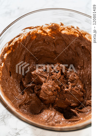 With a hand whisk, the ingredients are expertly mixed in a glass mixing bowl - creating this delectable Chocolate Bundt Cake. With a hand whisk, the ingredients are expertly mixed in a glass mixing bowl - creating this delectable Chocolate Bundt Cake. 120801489