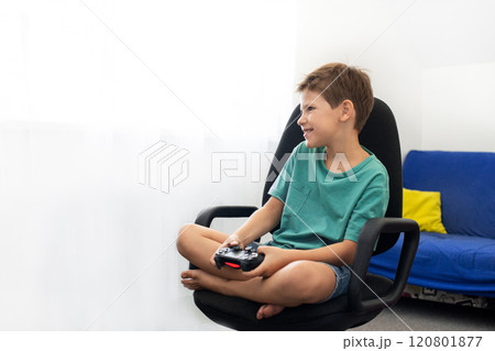 Boy plays a computer game with headphones and a joystick, game console. 120801877