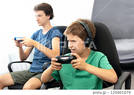 Teenager plays a computer game with headphones and a joystick, game console. 120801879